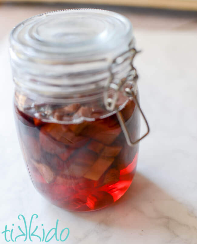 Mason jar filled with rhubarb and grain alcohol to make homemade rhubarb liqueur.