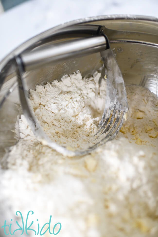 Butter being cut into dry ingredients with a pastry cutter to make rhubarb scones.