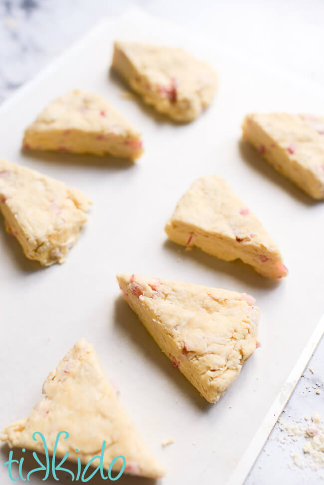 Unbaked rhubarb scones on a parchment lined cookie sheet.