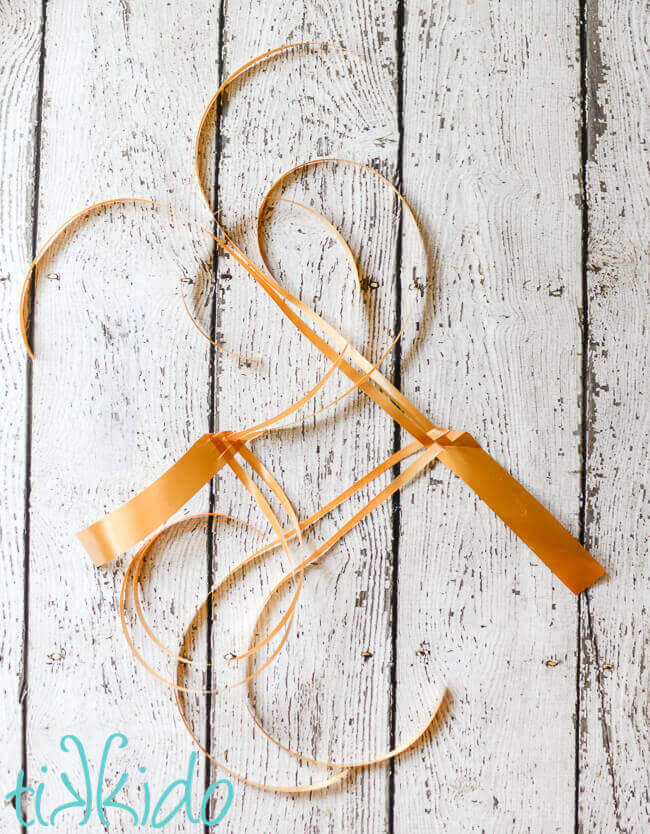 Golden ribbon being woven together to create a ribbon bird.