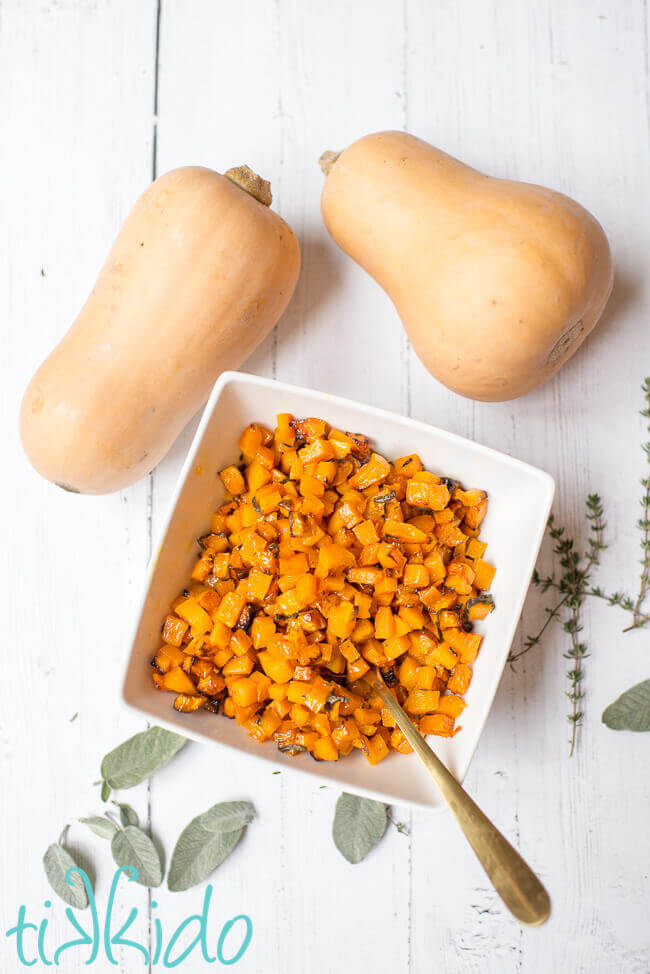 Roasted Butternut Squash Cubes tossed with browned butter and herbs in a white bowl.