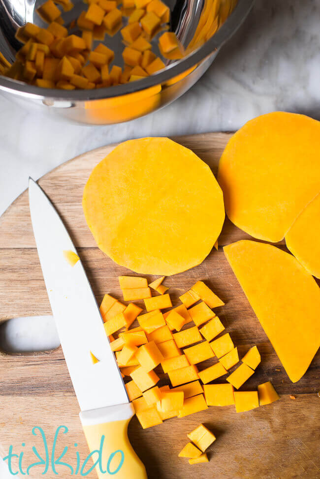 Butternut squash being cut into small cubes to be roasted.