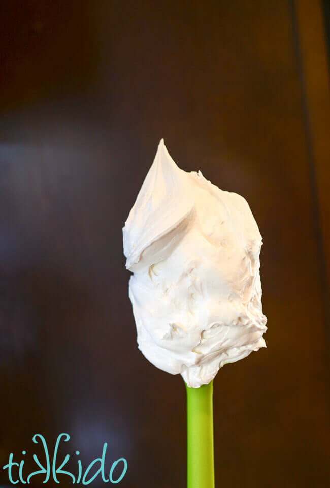 Royal Icing on a green spatula in front of a brown wooden backdrop