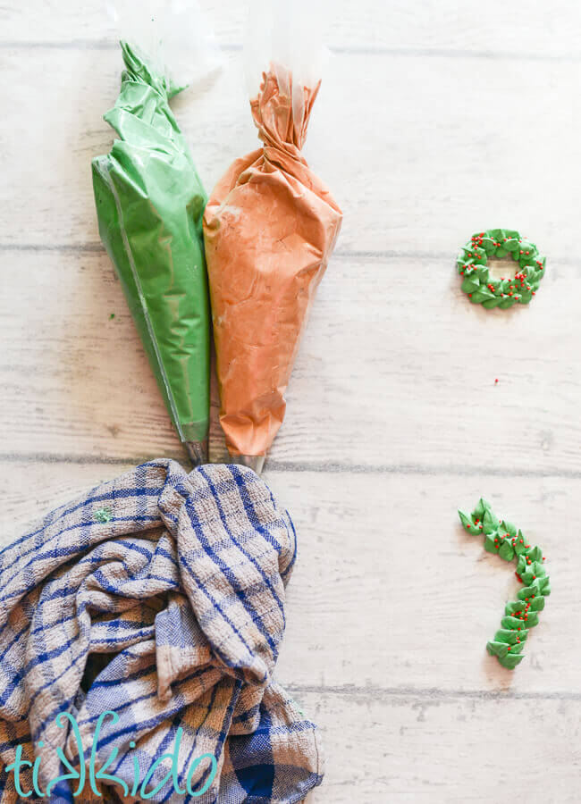 Two piping bags full of royal icing, with the tips covered by a damp kitchen towel.