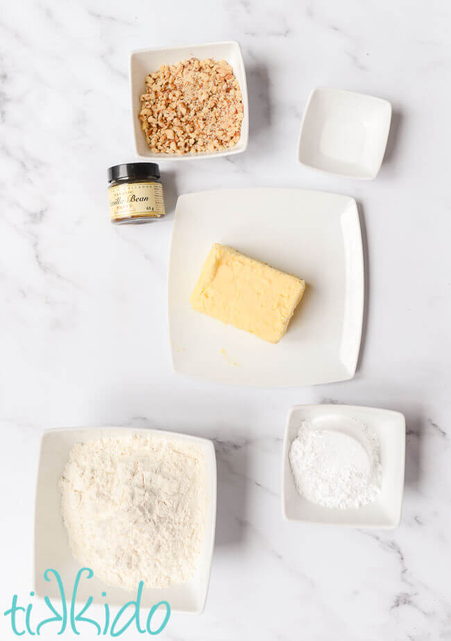 Russian Tea Cakes ingredients on a white marble background.