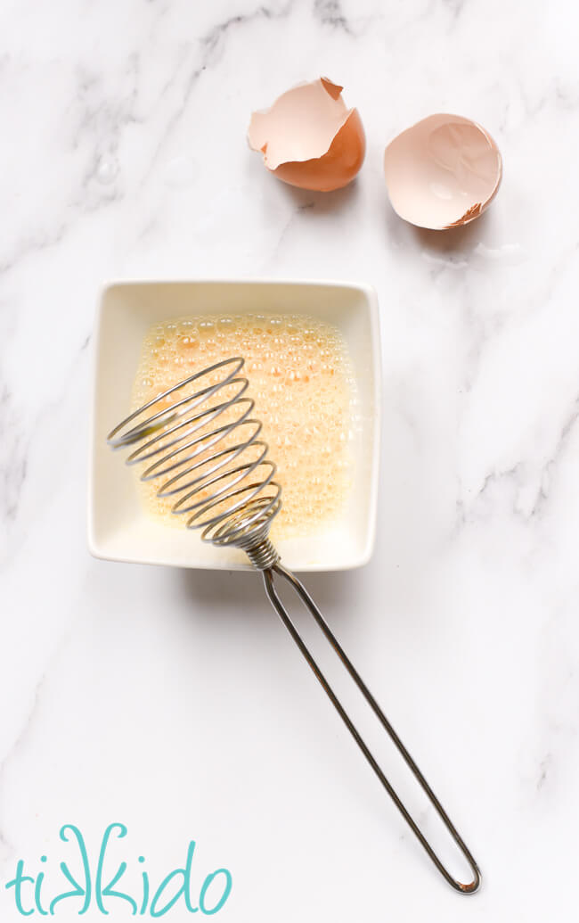 Egg beaten in a small white bowl for an easy scones recipe.