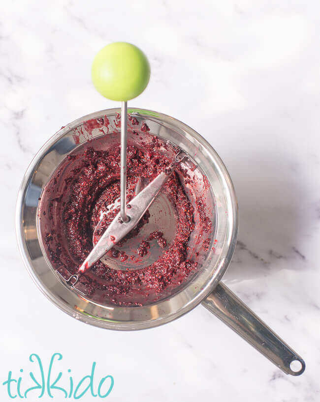 A food mill being used to remove blackberry seeds and make blackberry puree for making Seedless Blackberry Jam.