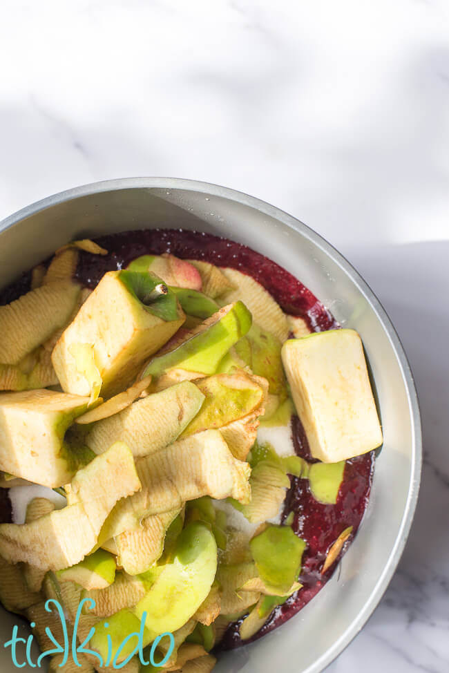 Apple peels and cores being added to blackberries and sugar to make homemade Seedless Blackberry Jam.