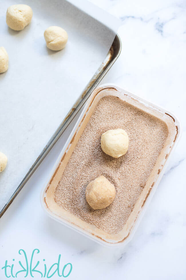 Snickerdoodle cookie dough balls being rolled in cinnamon sugar for the snickerdoodle cookie recipe.