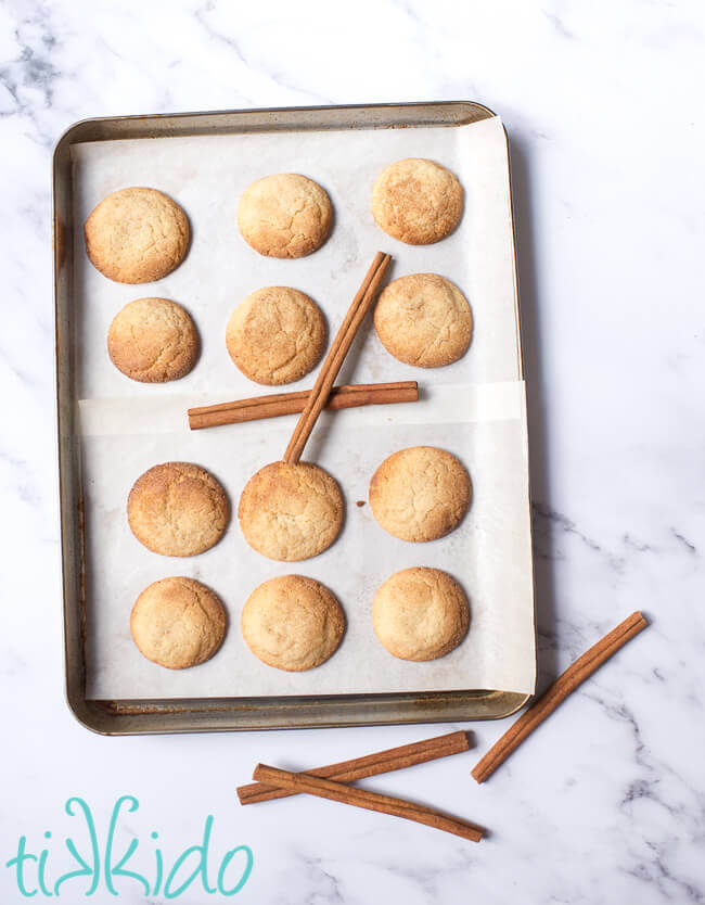Pan of baked snickerdoodle cookies next to cinnamon sticks.