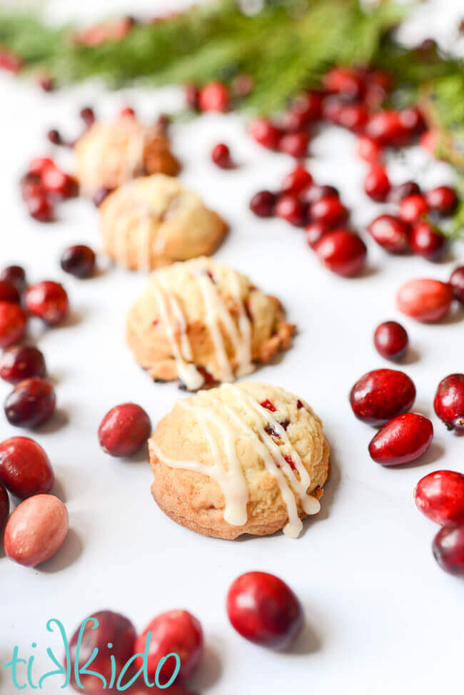 Cranberry cookies surrounded by fresh cranberries on a white marble background.
