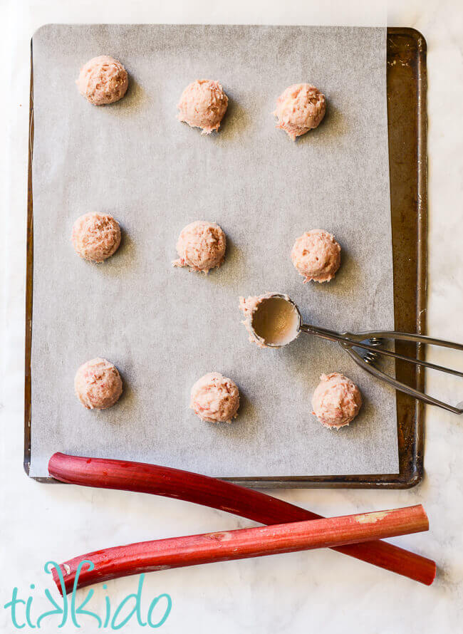 Batter for rhubarb cookies scooped on a parchment lined cookie sheet.