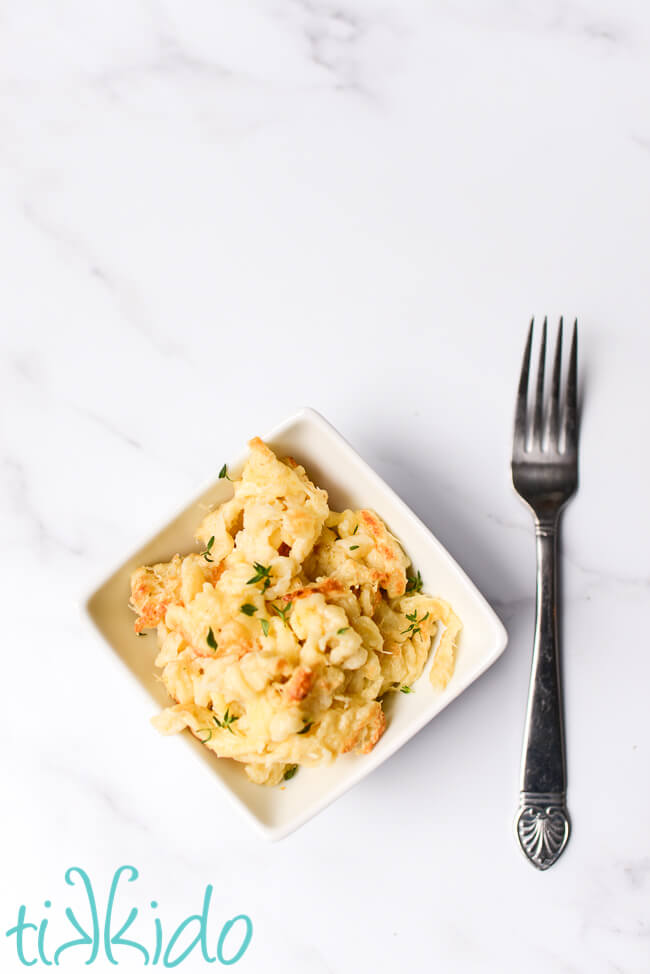 Kaese Spaetzle in a white bowl beside a fork.