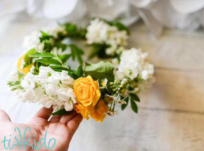 Hand holding a yellow and white fresh flower crown