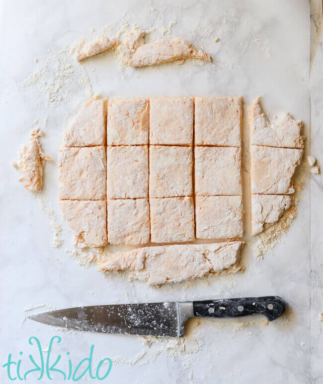 Sriracha cheddar biscuit dough cut into squares.