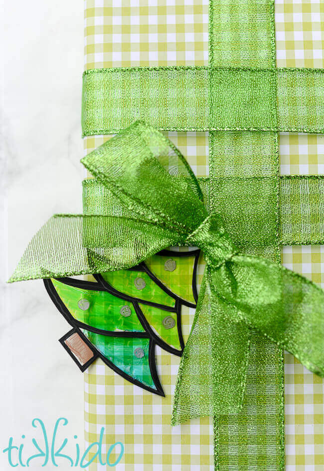 Faux stained glass gift tag shaped like a Christmas tree on a green and white wrapped Christmas present.