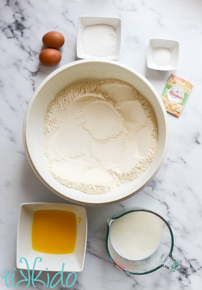 Ingredients for sticky bun dough on a white marble surface.