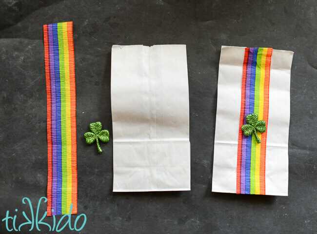 Decoration of white paper lunch bag with rainbow crepe paper and shamrocks.