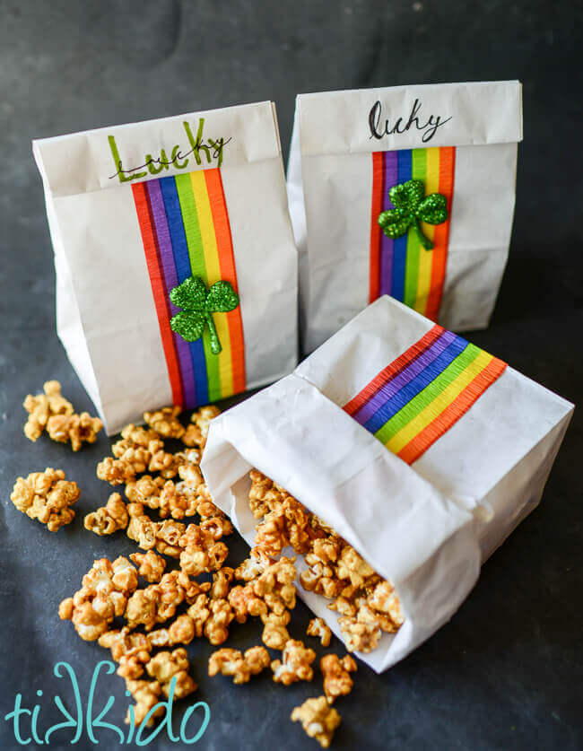 Homemade caramel corn in white paper bags decorated with rainbows and shamrocks.