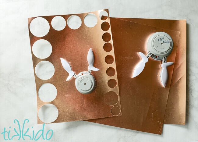Gold Scrapbook paper and two circle paper punches on a white marble background