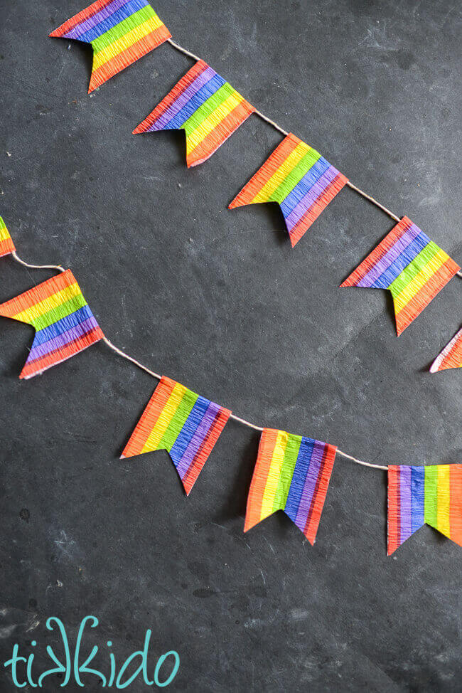 Rainbow flag bunting made with rainbow crepe paper against a black chalkboard backdrop