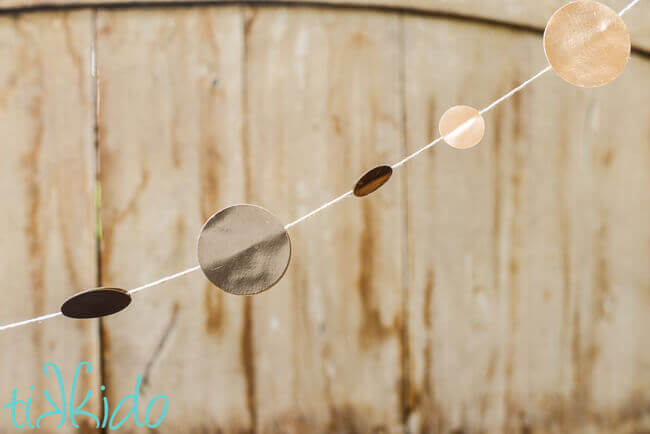 Gold Circle garland hung in front of a wooden background