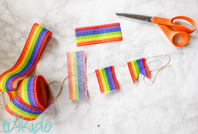 Rainbow crepe paper cut and assembled on string to make rainbow flag bunting.