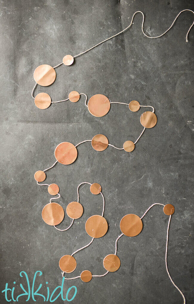 Gold coin garland displayed on a black chalkboard surface