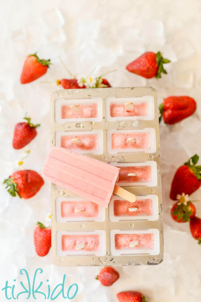 Strawberries and cream popsicle on top of filled popsicle mold.