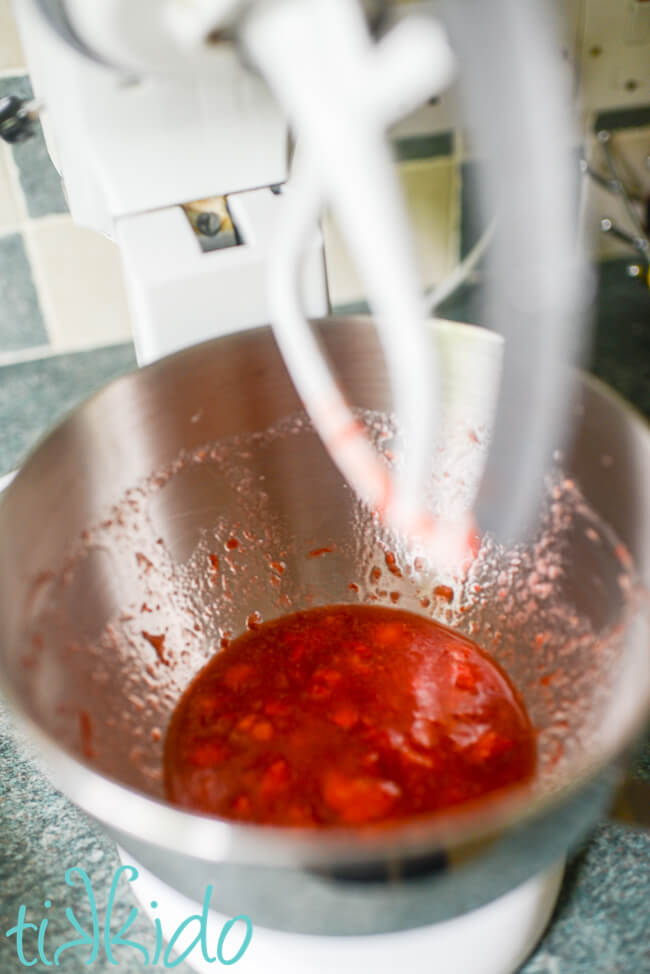 Strawberries being mashed in a Kitchenaid mixer to make Strawberry Cheesecake Popsicles.