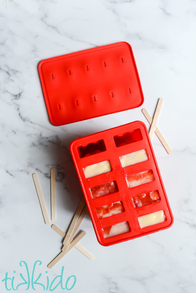 Strawberry puree and Jello cheesecake pudding in a popsicle mold, ready to be frozen to make Strawberry Cheesecake Popsicles.