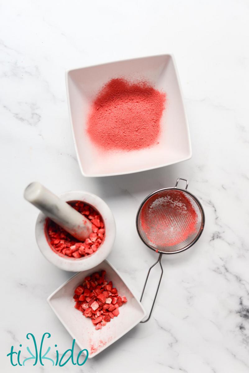 Freeze dried strawberries being ground in a mortar and pestle to make freeze dried strawberry powder.