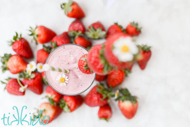 Top view of homemade strawberry milkshake surrounded by fresh strawberries.