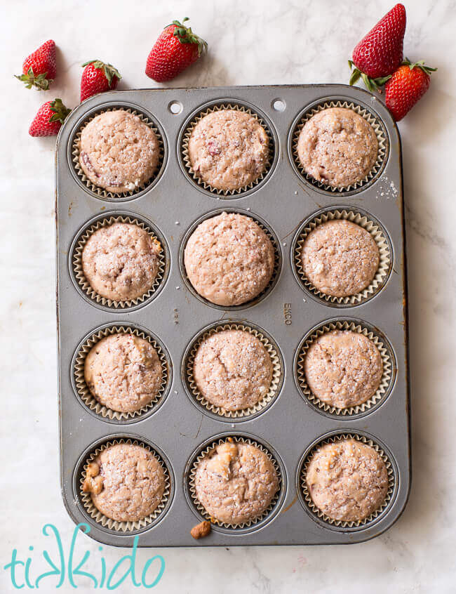 Baked pan of strawberry muffins surrounded by fresh strawberries.