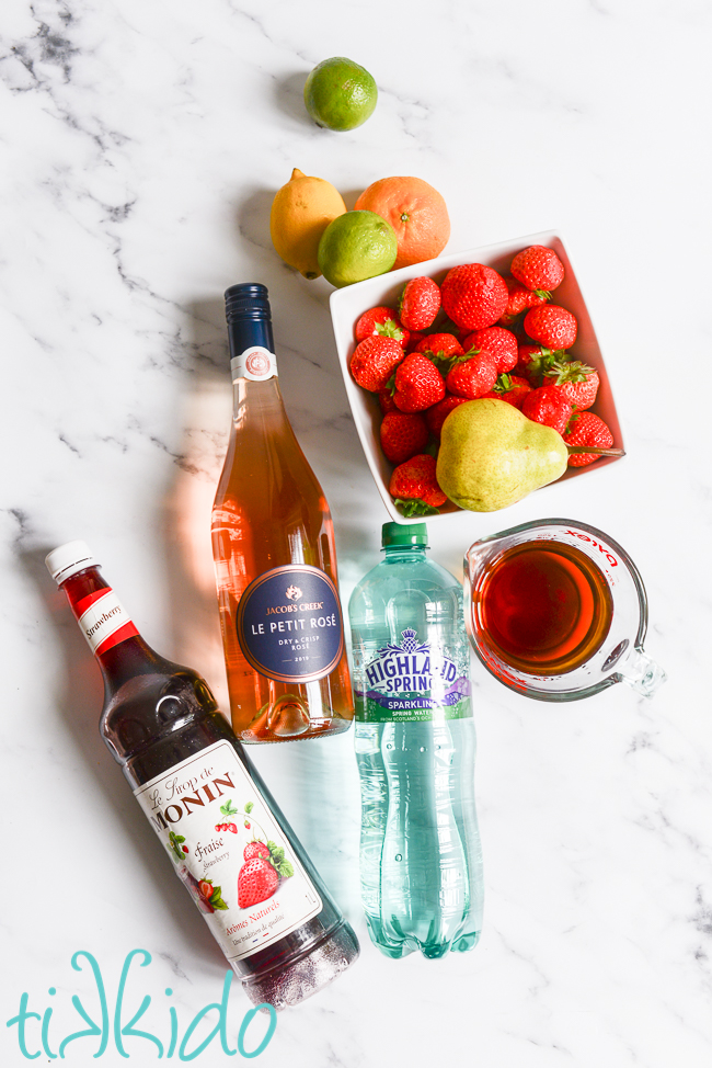 Ingredients for Strawberry Rosé Sangria on a marble surface.