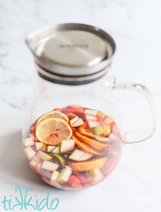 Sliced fruit soaking in brandy and strawberry syrup to make Strawberry Rosé Sangria.