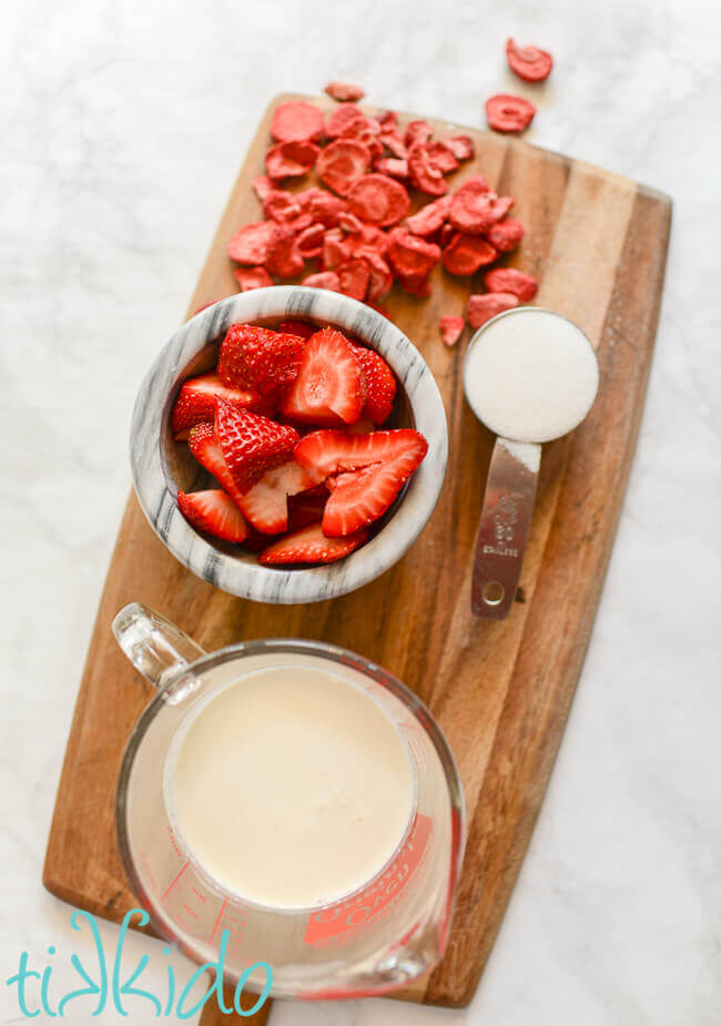 Ingredients for Strawberry Whipped Cream on a wooden cutting board.