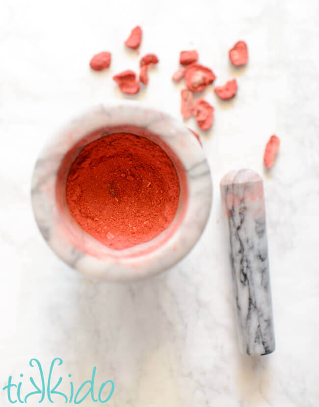 marble mortar and pestle filled with freeze dried strawberries ground into powder.