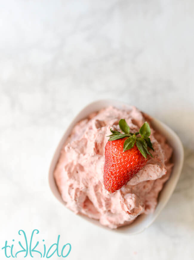 White bowl full of Strawberry Whipped Cream, topped with a strawberry.