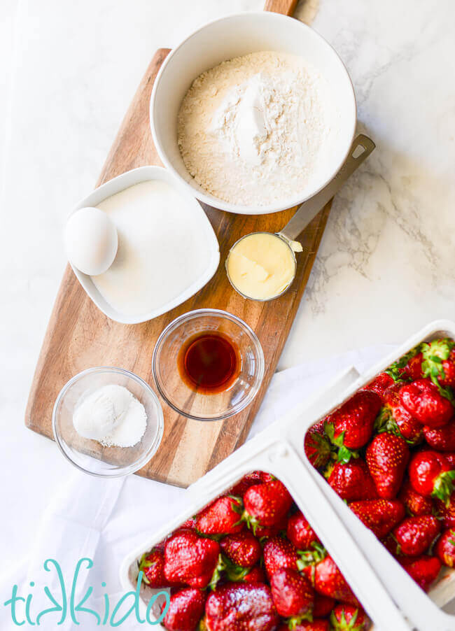 Strawberry shortcake ingredients on a white marble background.