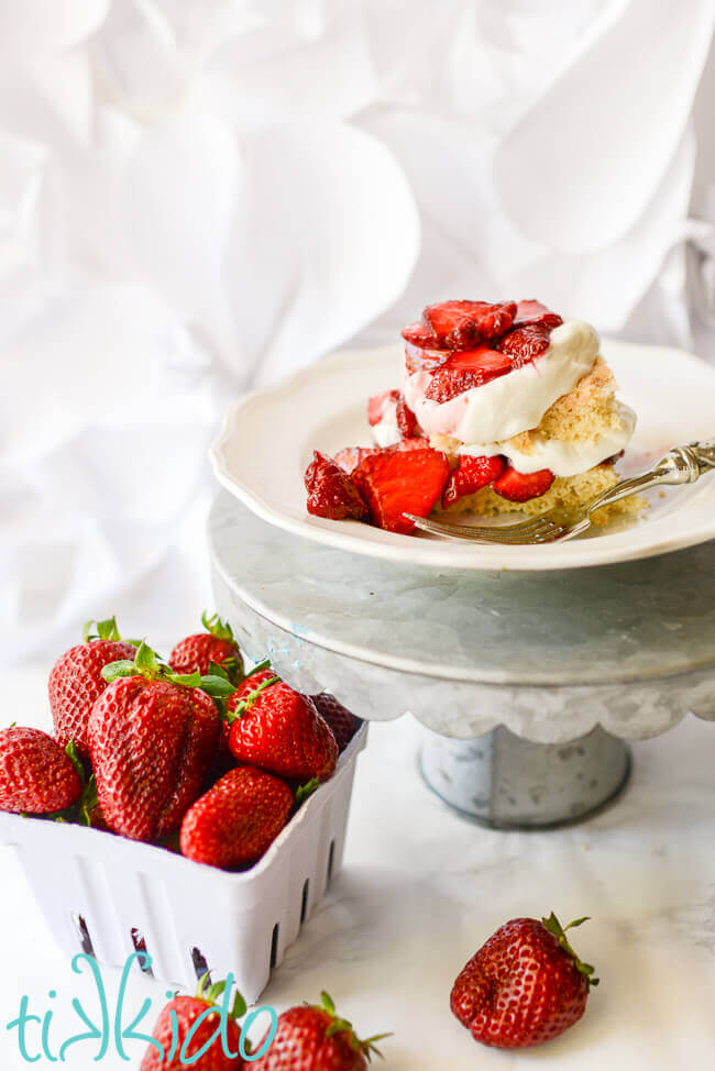 Homemade strawberry shortcake with fresh strawberries and whipped cream on a white plate.