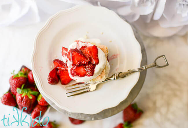 Homemade strawberry shortcake with fresh strawberries and whipped cream on a white plate.