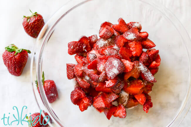Sliced strawberries in a bowl sprinkled with sugar.