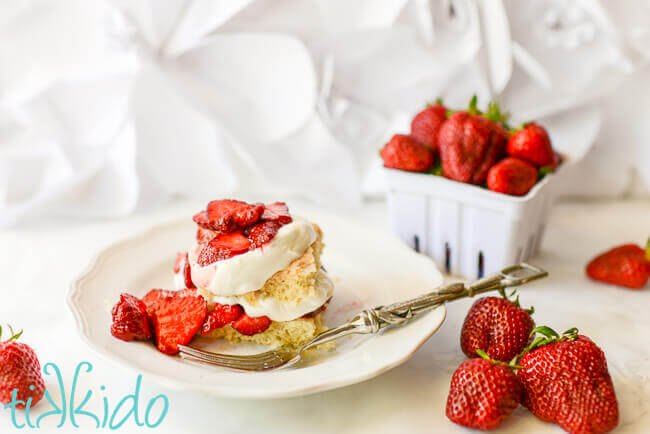 Homemade strawberry shortcake with fresh strawberries and whipped cream on a white plate.