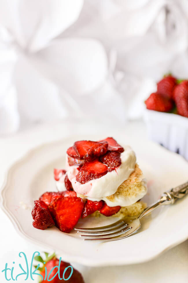 Homemade strawberry shortcake with fresh strawberries and whipped cream on a white plate.