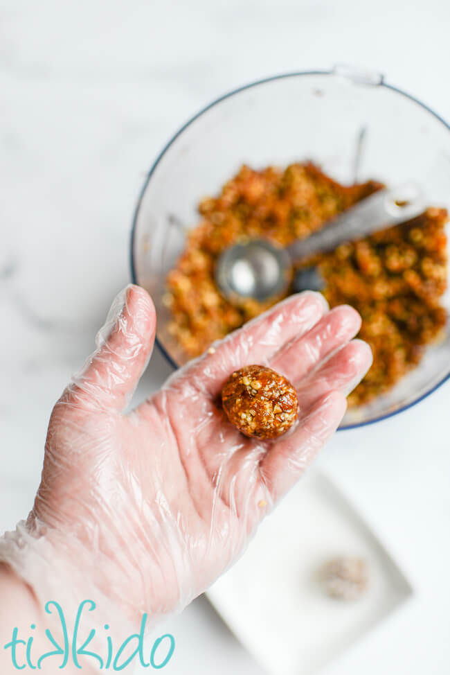 Sugar plums being rolled into a ball in a gloved hand.