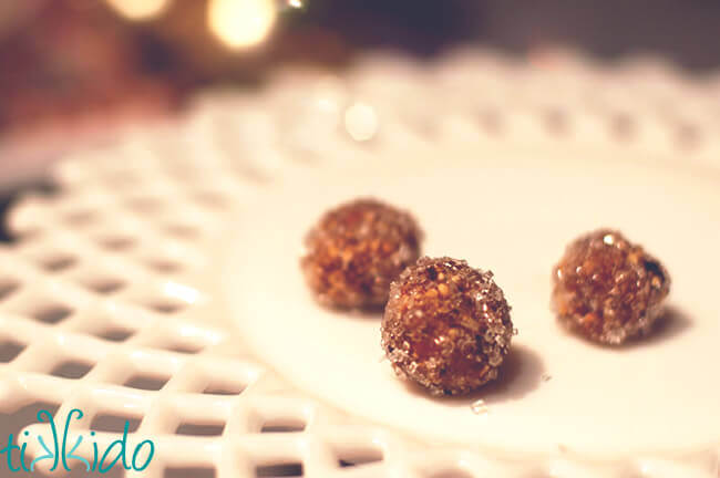 Three sugar plums made with a traditional sugar plum recipe on a white cake plate.