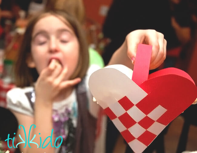 Little girl holding Swedish Paper Heart basket full of popcorn.