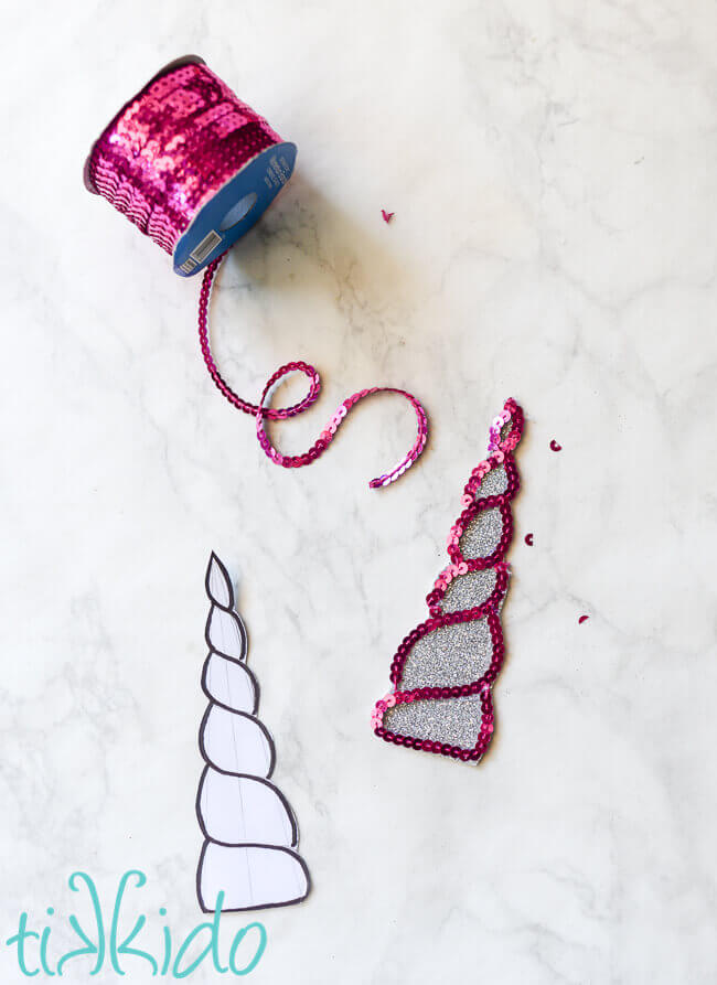 Foam unicorn horn being outlined with hot pink sequin string.