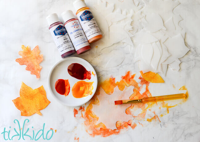 wafer paper leaves being painted with food coloring in fall colors.